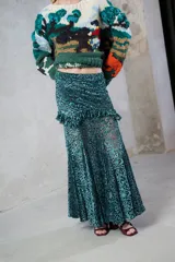 Falda larga de encaje de terciopelo color verde esmeralda, con diseño de caderín, volados decorativos y corte evasé con terminaciones en picos que aportan amplitud.