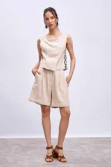 Short color beige de tiro alto, con pinzas delanteras y bolsillos laterales.