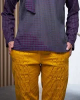 Pantalón babucha color beige de algodón, con corte a la cintura y piernas levemente amplias. Presenta textura de tablitas centrales y elásticos con broches inferiores que ajustan las piernas al tobillo.