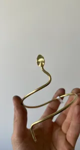 Brazalete rígido plateado con forma de serpiente enroscada.