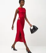 Vestido midi sin mangas color rojo, confeccionado en microfibra con elastano. Presenta un diseño drapeado en el lateral de la cintura con un adorno metálico en forma de gota, escote redondo y una abertura lateral en la falda.