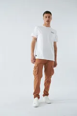 Pantalón cargo color beige, corte slim, con cierre y botón en la cintura, pasacintos, bolsillos cargo con botones y sin puños.