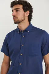 Camisa azul de manga corta, con cuello abotonado y bolsillo en el pecho.
