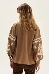 Camisa de calce holgado color marrón camel, confeccionada en Lyocell, con bordados blancos de estilo folclórico en las mangas.