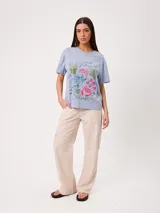 Remera celeste de corte holgado, con cuello redondo, manga corta y estampado frontal colorido de temática costera.