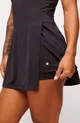 Vestido deportivo negro sin mangas, con escote en V y logo estampado en el pecho. Falda corta con short interno y bolsillos laterales. Incluye protección UV50+.