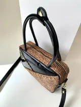 Cartera rígida negra con detalles en rojo y tachas plateadas. Tiene herrajes y cierre metálico plateado marca YKK, asa fina para llevar al hombro o en la mano y correa larga extra regulable. El interior es forrado, tiene un bolsillo con cierre enmarcado en cuero, y un segundo bolsillo plaqué.