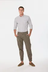 Pantalón de vestir color verde oliva, de corte recto, con bolsillos laterales y traseros. Se ajusta a la cintura con cinturón de cuero marrón.