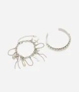Kit de dos pulseras rígidas de metal plateado, una decorada con incrustaciones de strass y otra con múltiples cadenas colgantes y dijes.
