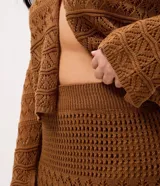 Pollera midi de tricot marrón con puntos calados y diseños geométricos, de corte levemente ajustado y cintura con pretina acanalada.