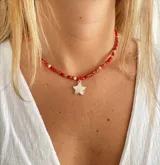 Collar corto de cuentas rojas, blancas y transparentes con dije de estrella plateada.