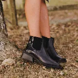 Bota corta tipo chelsea de cuero vacuno color negro, con puntera cuadrada, taco cuadrado de madera y detalle de textura grabada en el panel elástico lateral.