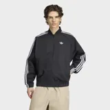 Campera deportiva Adidas modelo SST Adicolor Classics Cotton Twill, color negro con las clásicas tres tiras blancas en las mangas y el logo del Trifolio bordado en el pecho. Cuenta con cierre frontal y bolsillos.