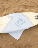 Remera de algodón color celeste claro, corte oversized, con estampado en la espalda que incluye el logo "TRIBU CO" y la frase "Beach Social Club".