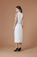 Vestido midi sin mangas, de cuello alto y textura plisada con ondas verticales. Presenta un corte entallado con un cinturón negro integrado que incluye una hebilla metálica dorada con el logo de la marca.