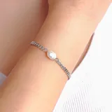 Pulsera de cadena plateada con un dije de perla barroca en el centro.