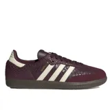 Championes Adidas Samba OG de color bordó con textura símil piel de serpiente y detalles en blanco marfil. Cuentan con las clásicas tres tiras laterales, inscripción 'SAMBA' en letras doradas, refuerzo de gamuza en la puntera y suela de goma marrón.