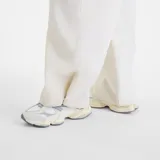 Pantalón cargo New Balance de corte amplio y tiro medio, confeccionado en tela técnica ligera de color blanco. Presenta cintura elástica con cordón ajustable, bolsillos laterales tipo cargo y diseño de pierna recta.