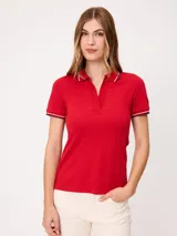 Remera polo color rojo de manga corta, con cuello camisero sin botones y ribetes a rayas en cuello y puños.