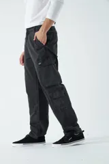Pantalón cargo de canvas en color negro, confeccionado en algodón grueso. Presenta diseño de tiro medio con múltiples bolsillos laterales tipo cargo y pasacintos en la cintura.