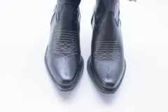 Botas estilo texanas de caña media, confeccionadas en cuero con estampado animal print tipo vaca en blanco y negro. Presentan un diseño de punta fina y taco cuadrado.