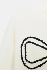 Sudadera de cuello redondo y manga larga, color blanco, con un gran lazo negro en contraste bordado en el delantero. Los acabados son en rib.