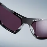 Lentes de sol de diseño envolvente con montura de acero inoxidable en color gunmetal y lentes de nylon color violeta. Presentan un diseño deportivo con detalles perforados en la parte superior del marco y patillas de acetato.