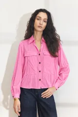 Camisa de manga larga color fucsia, con bolsillos frontales con solapa, cuello camisero y cierre frontal con botones oscuros.