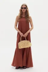 Vestido largo de lino marrón, sin mangas, con cuello a la base y canesú en la espalda. Cuenta con godets en el ruedo que le aportan movimiento y amplitud.