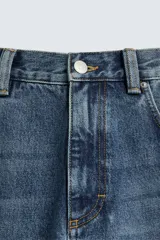 Jeans de corte relaxed fit en denim de algodón, color azul medio lavado. Presenta bordados florales en color blanco o crudo distribuidos en las piernas. Modelo de cinco bolsillos con cierre frontal de cremallera y botón.