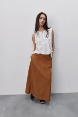 Falda larga color tostado, de línea evasé y silueta amplia, con diseño de paneles y costuras visibles pespunteadas.