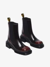 Bota Chelsea color bordó con puntera cuadrada, suela angular y tacón bajo. Presenta inserciones elásticas laterales y el clásico tirador de talón amarillo con el logo de la marca.