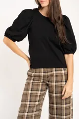 Remera de algodón negro con mangas cortas abullonadas, cuello redondo y costura central frontal.