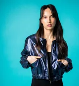 Bomber azul marino de cuero con mangas ranglán, bolsillos laterales, elástico en la cintura y cierre metálico delantero.