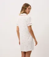 Camisón corto color blanco marfil con estampa floral sutil, cuello solapa, mangas cortas y cierre frontal con botones. Cuenta con ribetes en contraste en cuello y puños.