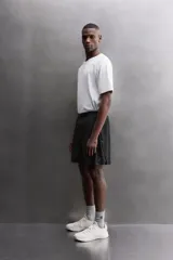 Pantalones cortos negros de tejido técnico perforado, ligeros y elásticos. Cuentan con cintura elástica ajustable con cordón interior, bolsillos frontales, bolsillo trasero de seguridad con cierre de cremallera, perneras con laterales perforados para transpirabilidad, bajo con acabado termofijado y aberturas laterales. Incluye detalle de logo estampado en la pernera.