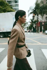 Blazer de corte clásico con cuello solapa y manga larga, confeccionado en tejido con patrón de espiga en tonos tierra y líneas verticales en color salmón. Cuenta con bolsillos delanteros y cierre frontal con botones ocultos.