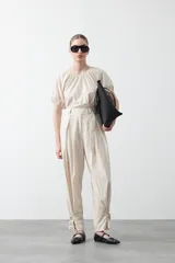 Pantalón baggy negro de silueta relajada con volumen amplio y caída fluida. Presenta detalles de ajuste con hebillas metálicas en el bajo y un cinturón de tela con hebilla metálica en la cintura.