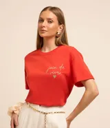 Remera roja de algodón con mangas cortas y cuello redondo. Presenta un bordado con la frase "joie de vivre" y un corazón de strass en el pecho.