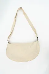 Cartera tipo bandolera de tela con diseño semicircular, cuenta con una correa larga ajustable y cierre superior.