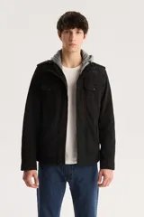 Campera militar negra con capucha gris de algodón, cierre frontal con cremallera y botones a presión, cuatro bolsillos frontales con solapa y charreteras en los hombros.