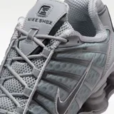 Championes Nike Shox TL en tonos gris lobo y gris hierro, con diseño de amortiguación Shox en la suela y detalles de malla en la parte superior.