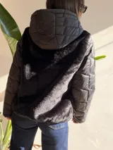 Campera con cuerpo de piel sintética tipo teddy y mangas acolchadas. Presenta cierre frontal, capucha y diseño de corte recto.