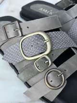 Sandalias bajas de cuero color gris con tres tiras horizontales con hebillas metálicas y plantilla anatómica.