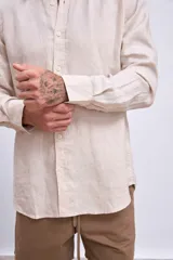 Camisa de lino color crudo, de corte recto, con cuello clásico y mangas largas.