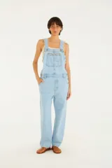 Enterito largo de jean celeste con tirantes ajustables con hebillas metálicas, bolsillo frontal y corte amplio.