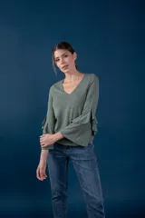 Blusa de punto fino color verde melange, con escote en V y mangas largas anchas adornadas con volados en cascada.