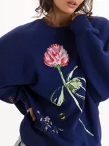 Buzo azul marino de corte oversize y cuello redondo, con diseño gráfico estampado de una flor y una abeja en el frente.