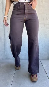 Jean de corte recto y tiro alto en color marrón chocolate, con costuras a contratono y cierre frontal con botón metálico.