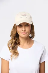 Gorro con visera de lona color beige, con bordado frontal con la frase "Sun Shines On Everyone Legacy Woman".